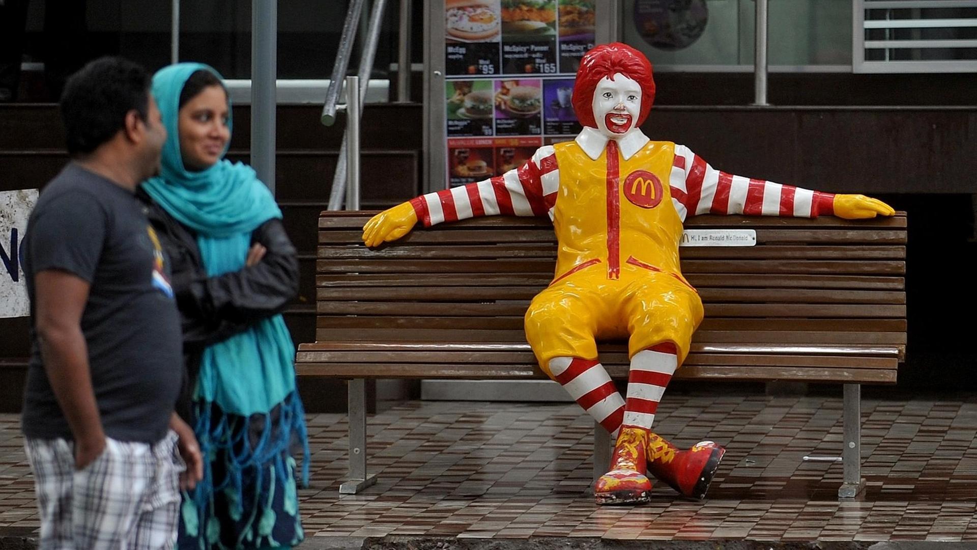 Ein indisches Paar geht an einer Mc Donalds Filiale in Pune vorbei. Ein indisches Paar geht an einer Mc Donalds Filiale in Pune vorbei.