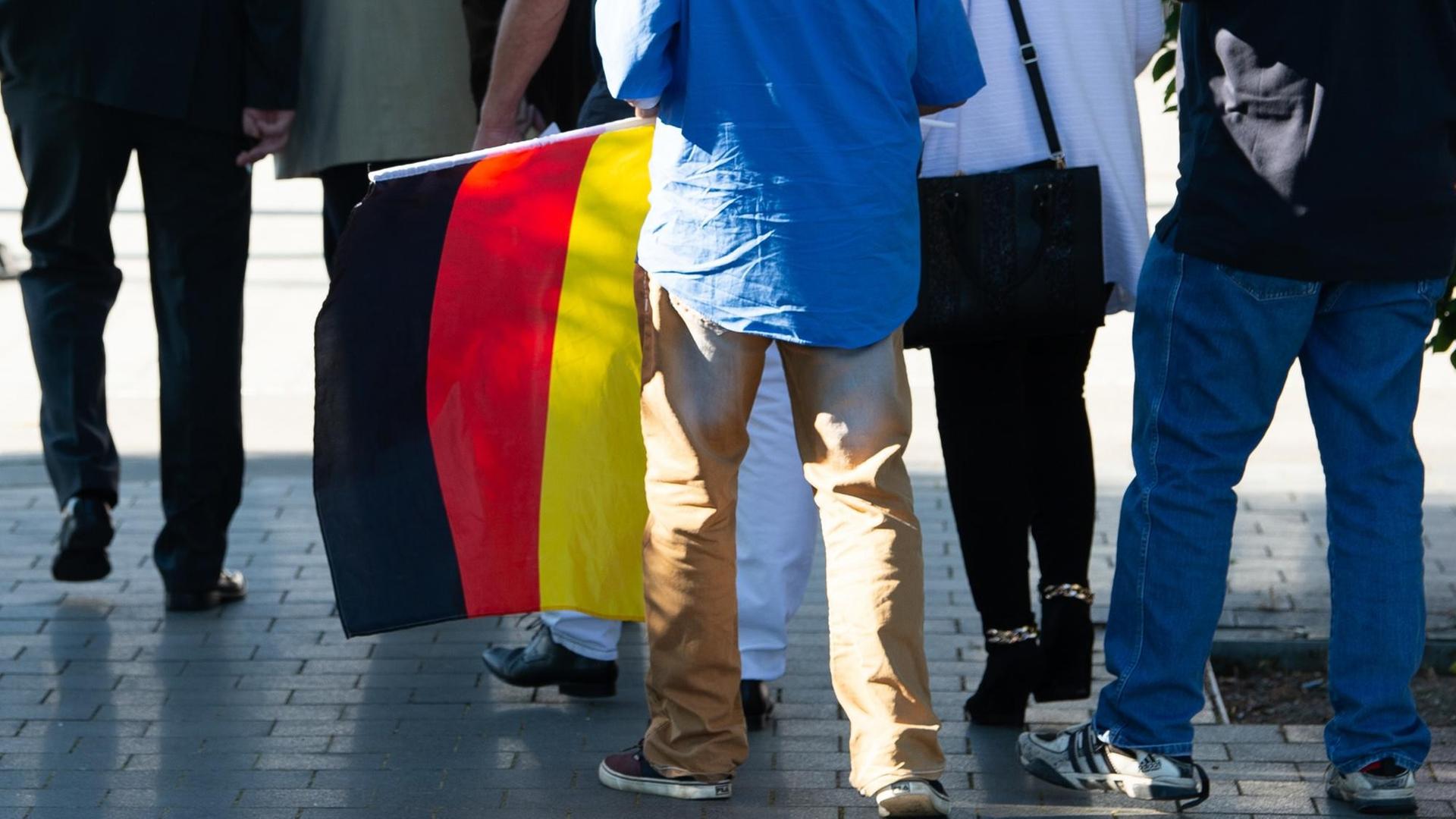 06.07.2019, Thüringen, Leinefelde: Ein Teilnehmer mit einer Deutschland-Flagge kommt zum Kyffhäusertreffen der AfD-Gruppierung "Der Flügel". 06.07.2019, Thüringen, Leinefelde: Ein Teilnehmer mit einer Deutschland-Flagge kommt zum Kyffhäusertreffen der AfD-Gruppierung "Der Flügel".