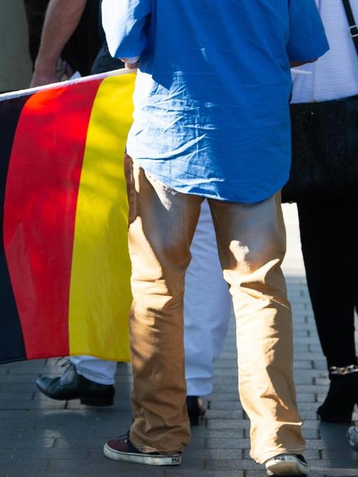 06.07.2019, Thüringen, Leinefelde: Ein Teilnehmer mit einer Deutschland-Flagge kommt zum Kyffhäusertreffen der AfD-Gruppierung "Der Flügel".