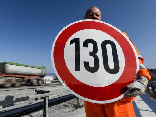 Ein Straßenwärter hält an der Autobahn A81 am Hegaublick ein Schild mit der Aufschrift "130" in den Händen.