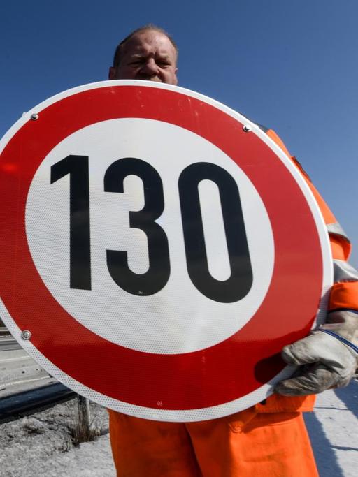 Ein Straßenwärter hält an der Autobahn A81 am Hegaublick ein Schild mit der Aufschrift "130" in den Händen