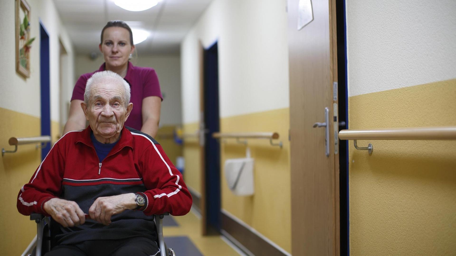 Senior, 87 Jahre, im Rollstuhl im Altenheim mit einer Krankenpflegerin.