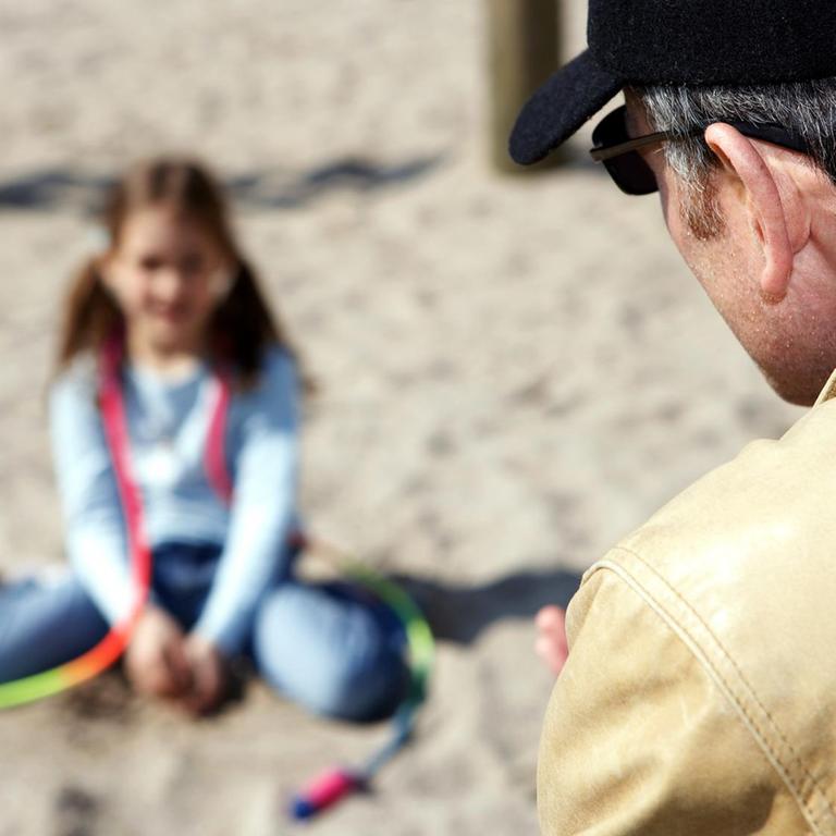 Ein fremder Mann spricht auf einem Spielplatz ein kleines Mädchen an
