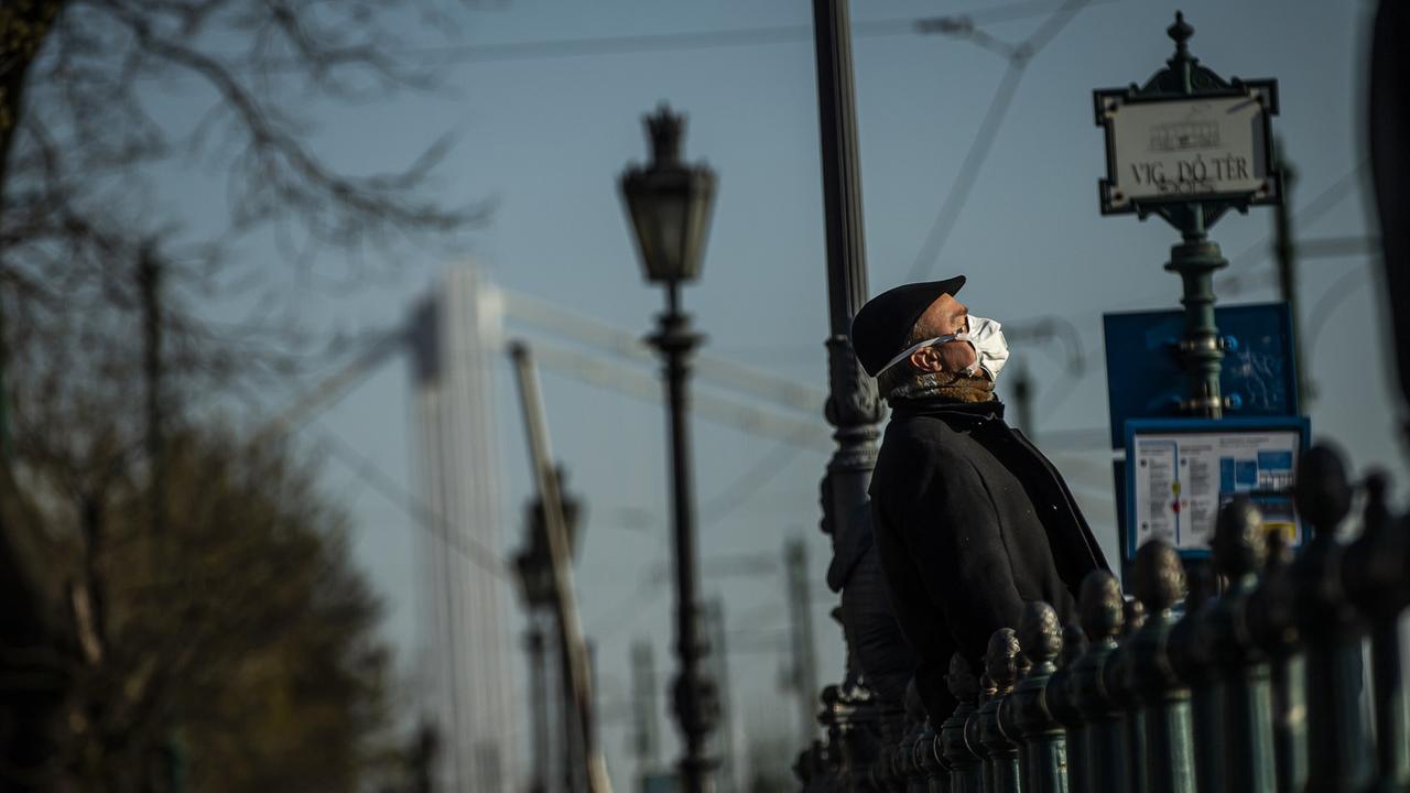 Ein Mann mit Schutzmaske genießt am 1. April in Budapest die Sonne.