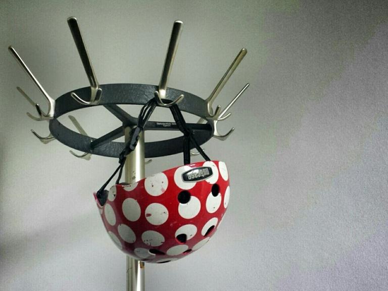 An einer Garderobe hängt ein gepunkteter Fahrradhelm.