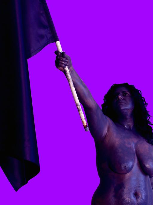 Die Künstlerin CANAN hält - nackt - eine Flagge in die Luft