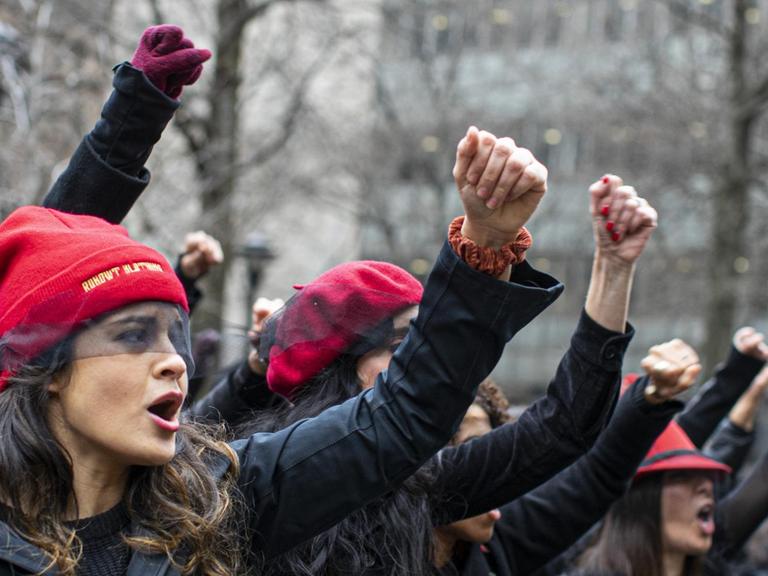 Frauen protestieren und singen, mit erhobenen Fäusten, vor dem Gerichtsgebäude