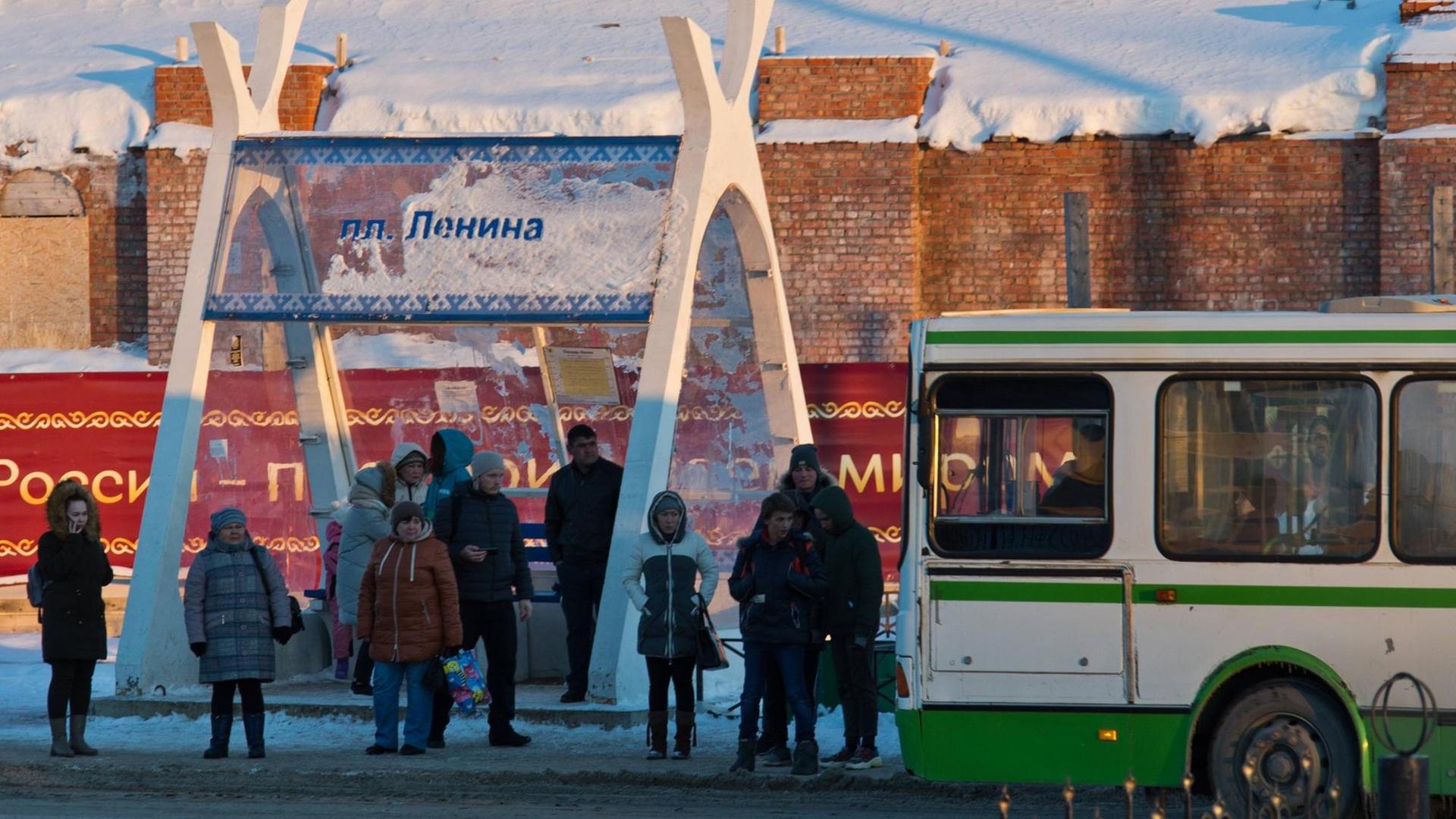 Menschen warten in Naryan-Mar im Autonomen Kreis der Nenzen auf den Bus Menschen warten in Naryan-Mar im Autonomen Kreis der Nenzen auf den Bus