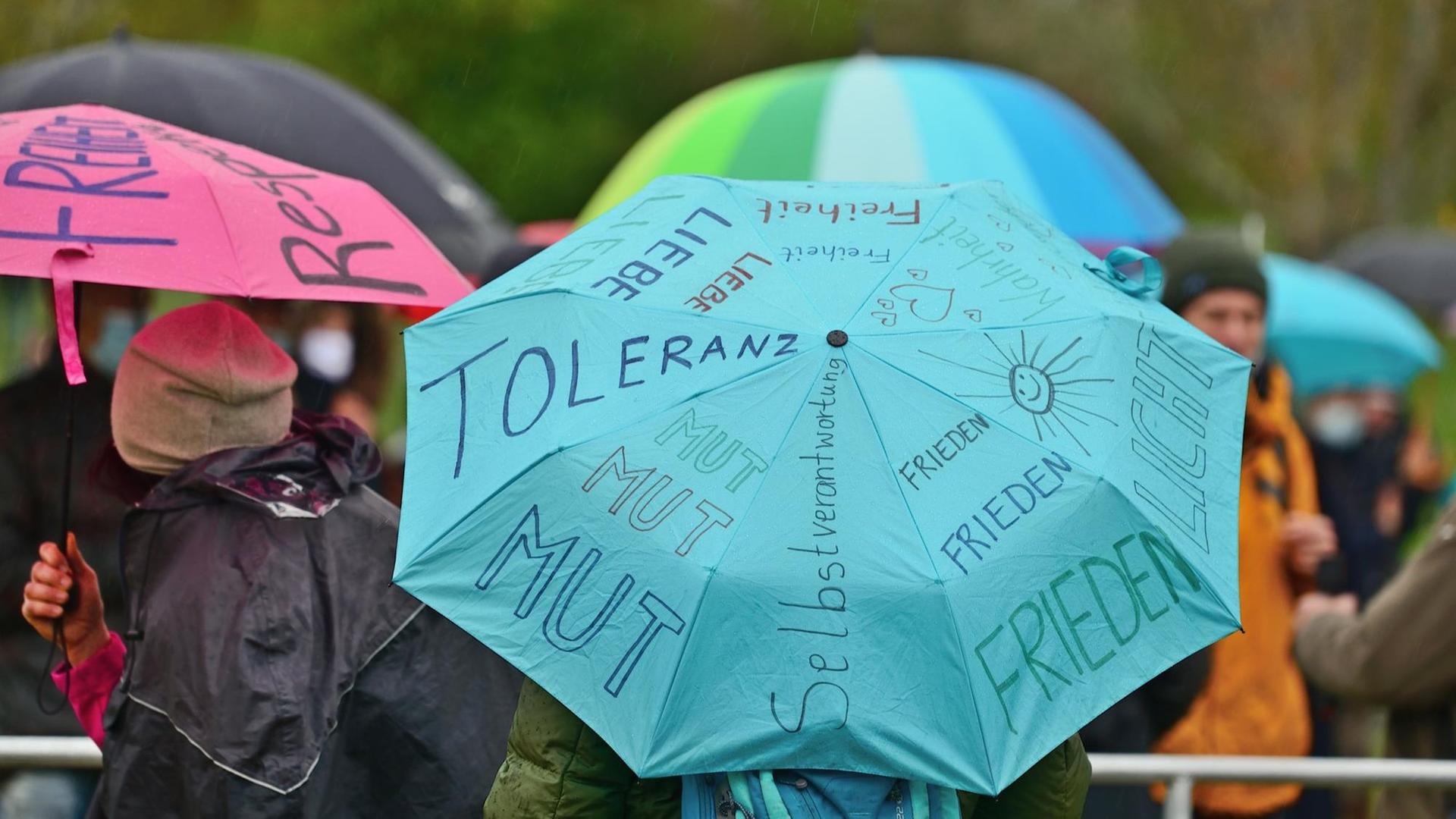 Auf einem blauen Regenschirm sind u.a. die Worte Frieden, Mut, Toleranz und Liebe zu lesen.