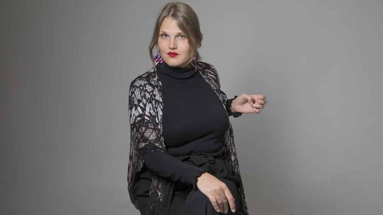 Aleksa Lundberg, eine Frau mit mittelblonden, langen Haaren, sitzt vor grauem Hintegrund auf einem Stuhl und blickt herausfordernd in die Kamera. Aleksa Lundberg, eine Frau mit mittelblonden, langen Haaren, sitzt vor grauem Hintegrund auf einem Stuhl und blickt herausfordernd in die Kamera.