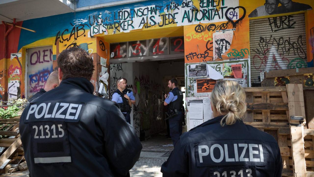 Polizisten vor einem Haus mit Graffiti