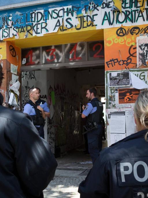 Polizisten vor einem Haus mit Graffiti