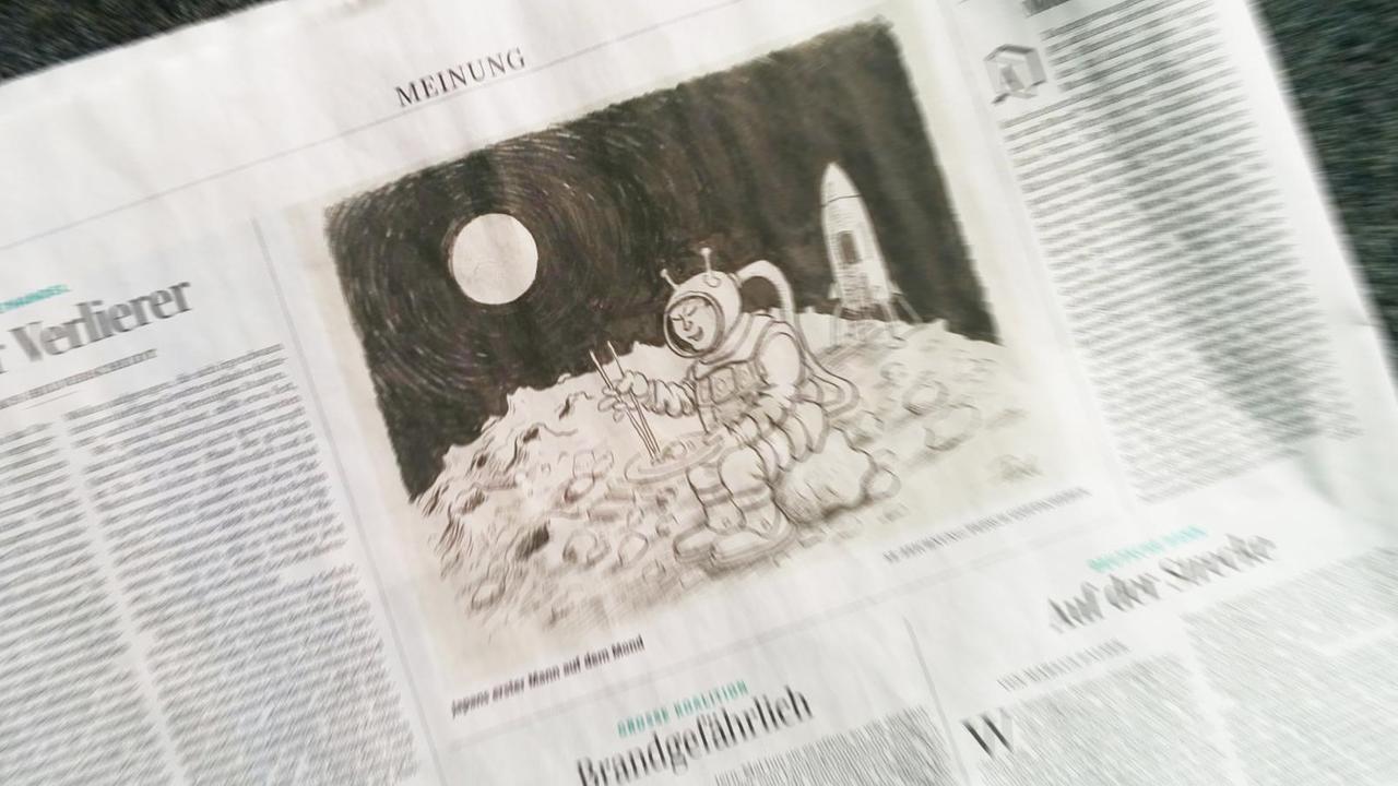 Eine Zeitungsseite der SZ mit einer Karikatur, die einen Astronauten mit Schlitzaugen zeigt, der auf dem Mond mit Stäbchen Sushi isst. Eine Zeitungsseite der SZ mit einer Karikatur, die einen Astronauten mit Schlitzaugen zeigt, der auf dem Mond mit Stäbchen Sushi isst.