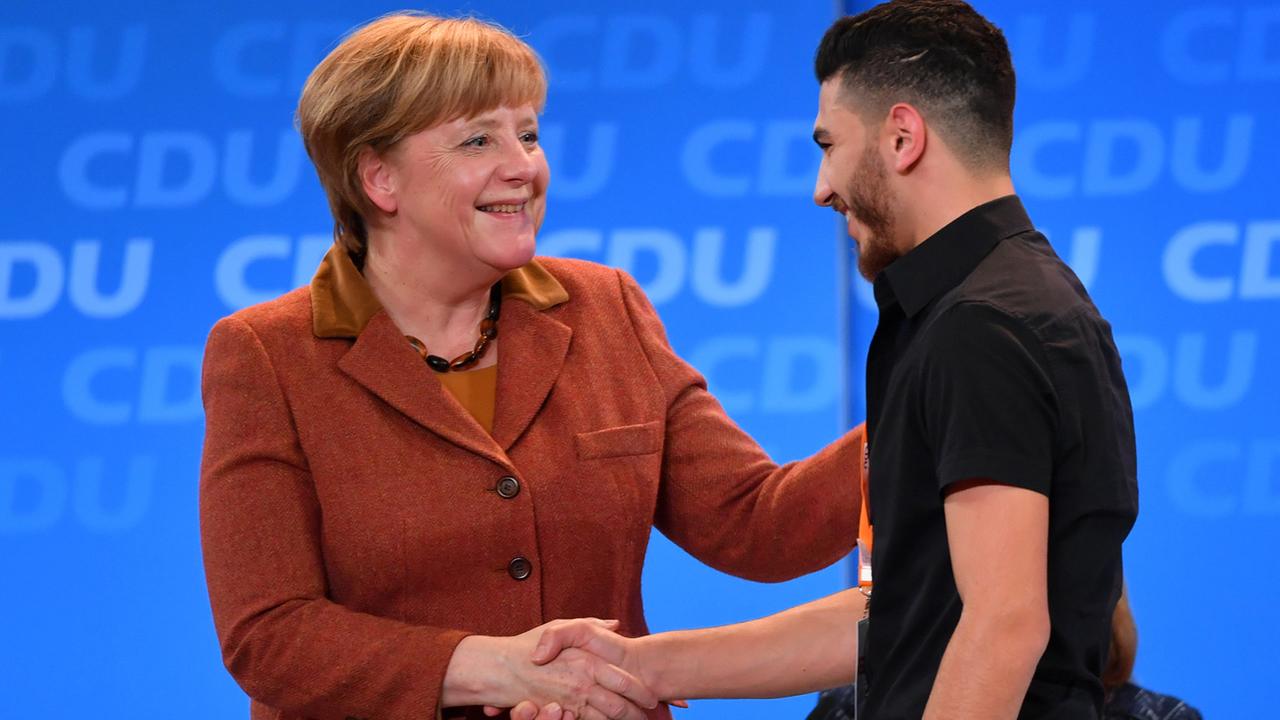 Bundeskanzlerin Angela Merkel begrüßt einen jungen Mann aus Aleppo bei der CDU-Regionalkonferenz in Jena.