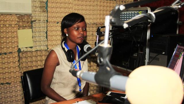 Eine Moderatorin sitzt vor einem Mikrofon im Studio des Kenianischen Bürgersenders "Mtaani FM"