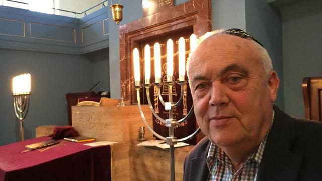 Der Vorsitzende der Thüringer jüdischen Landesgemeinde trägt eine Kippa, er steht vor einem siebenarmigen Leuchter