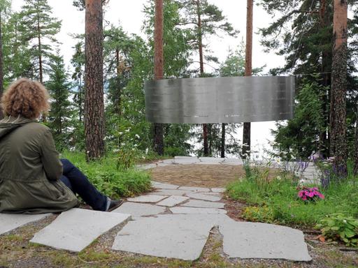 Eine Frau sitzt am 05.08.2015 auf der Insel Utøya (Norwegen) vor einem stählernen Ring, in den die Namen der Opfer der Terroranschläge eingraviert sind . Vier Jahre nach den Terroranschlägen von Anders Behring Breivik lädt die Jugendorganisation der norwegischen Arbeiterpartei (AUF) wieder zu einem Sommerlager auf der Insel Utøya ein.
