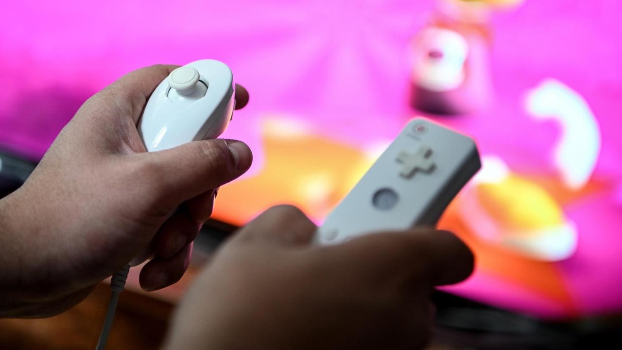 Ein junger Mann spielt mit einer Spielekonsole. Ein junger Mann spielt mit einer Spielekonsole.