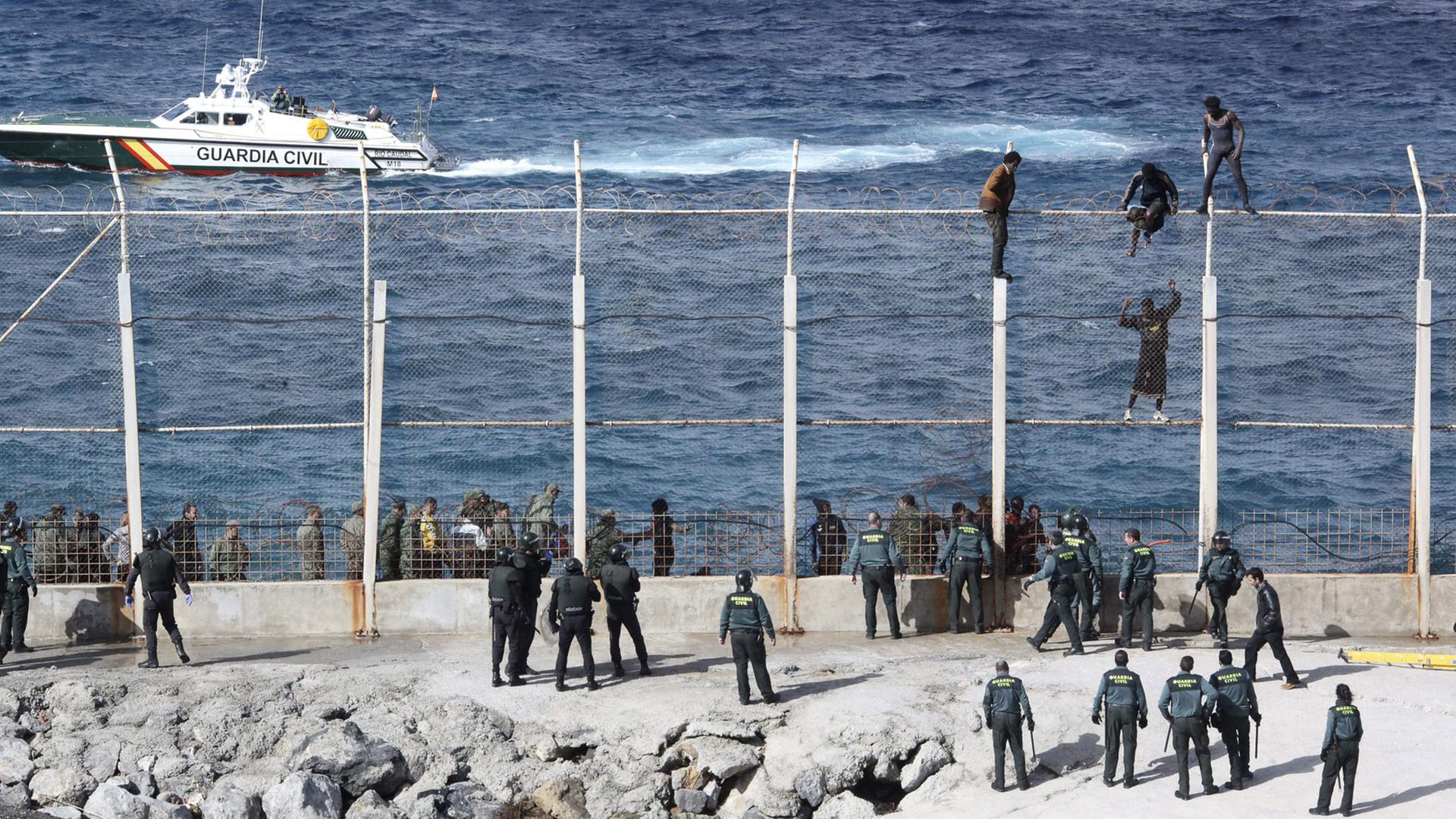 Menschen versuchen am 3.2.2015, den Grenzzaun der spanischen Exklave Ceuta in Nordafrika zu überwinden.