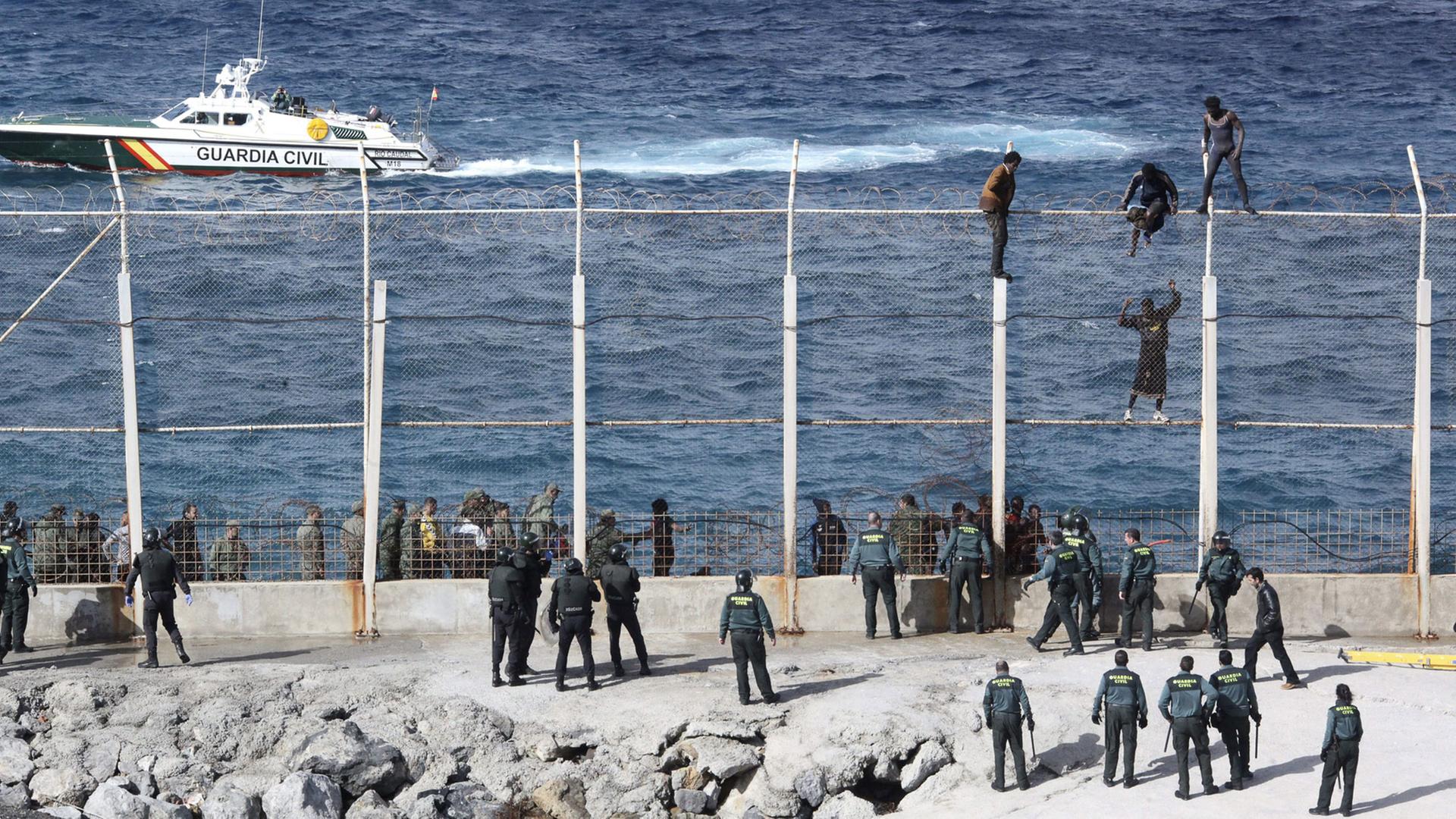 Menschen versuchen am 3.2.2015, den Grenzzaun der spanischen Exklave Ceuta in Nordafrika zu überwinden. Menschen versuchen am 3.2.2015, den Grenzzaun der spanischen Exklave Ceuta in Nordafrika zu überwinden.