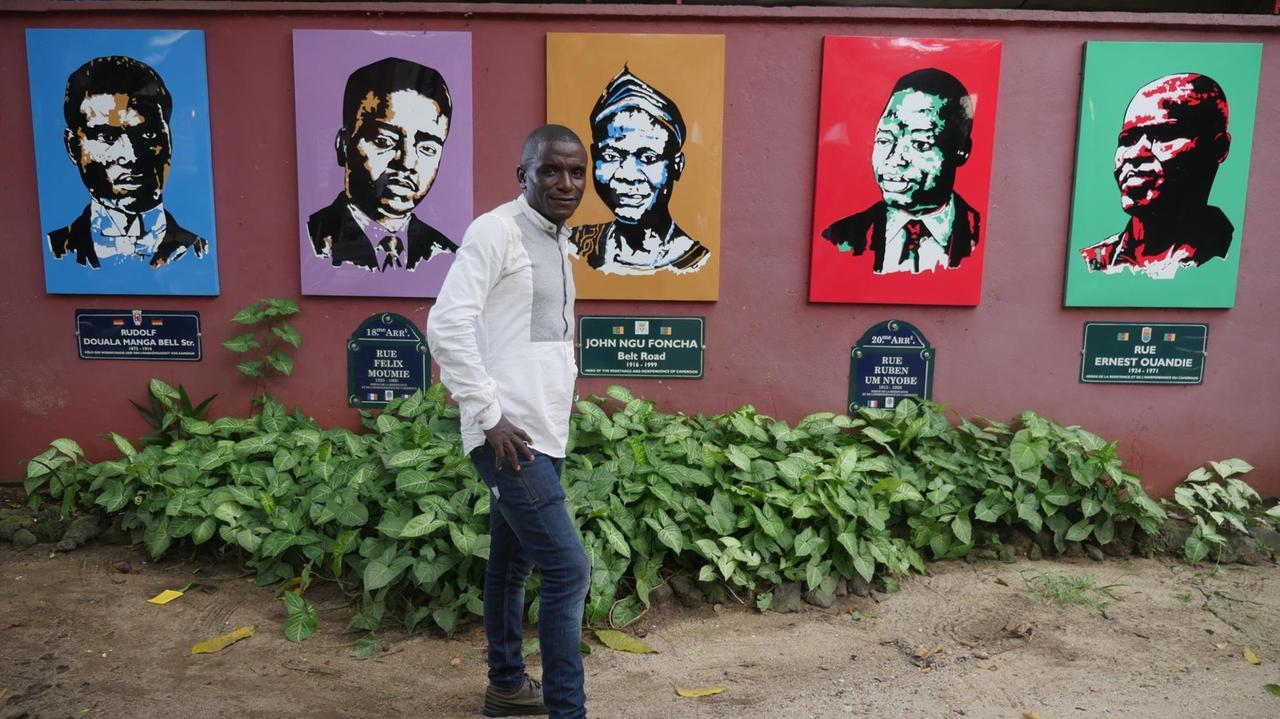 Filmemacher Roméo Ghislain Zafack vor dem Kunstwerk "Kamerunische Helden" - ganz links Rudolf Douala Manga Bell.