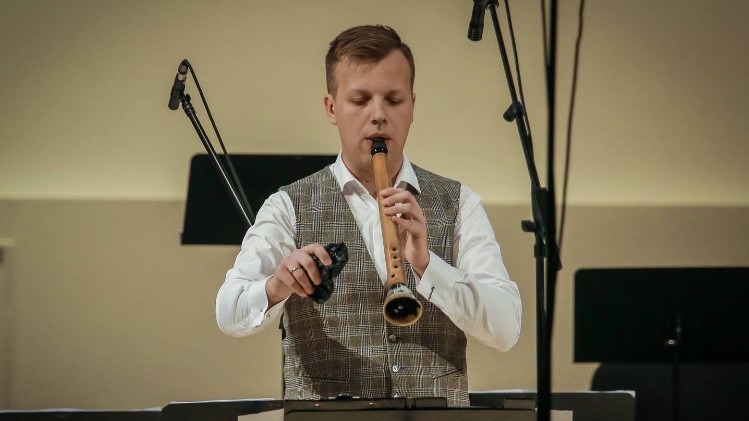 Ein Mann spielt ein flötenartigen Instrument aus Holz und Horn hinter einem Notenständer. Ein Mann spielt ein flötenartigen Instrument aus Holz und Horn hinter einem Notenständer.