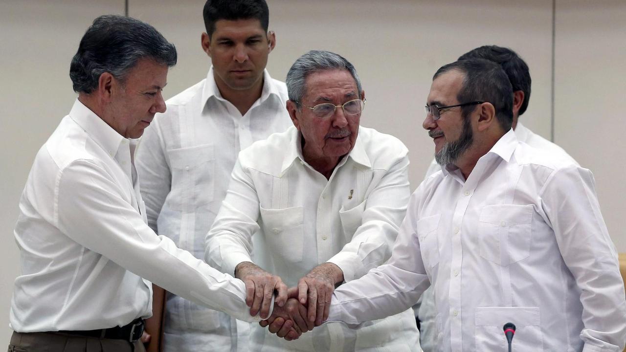 Der kubanische Präsident Raul Castro (M.) hält die Hände des kolumbianischen Präsidenten Juan Manuel Santos (l.) und des FARC-Führers Rodrigo Londono 'Timochenko' Echeverri (r.) Der kubanische Präsident Raul Castro (M.) hält die Hände des kolumbianischen Präsidenten Juan Manuel Santos (l.) und des FARC-Führers Rodrigo Londono 'Timochenko' Echeverri (r.)