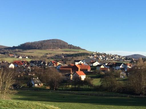 Zwischen sanften Hügeln und in Mitten grüner Wiesen liegt der Ort Nüsttal in Hessen.