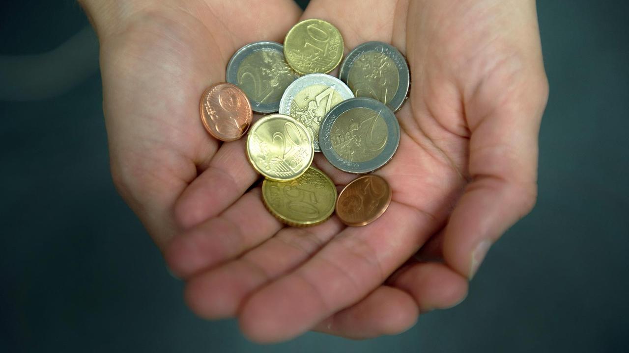Eine Frau hält 8,84 Euro in Münzen in ihren Händen. Eine Frau hält 8,84 Euro in Münzen in ihren Händen.