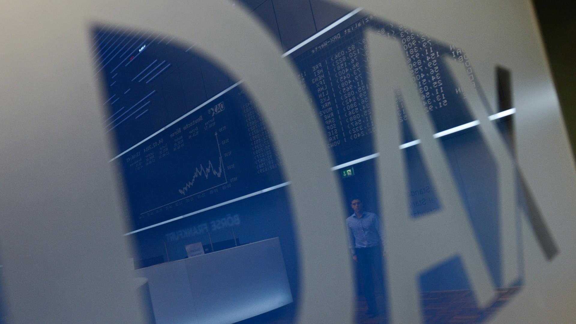 In einem Schild mit dem Dax-Logo spiegelt sich der Frankfurter Börsensaal mit der Kursanziege