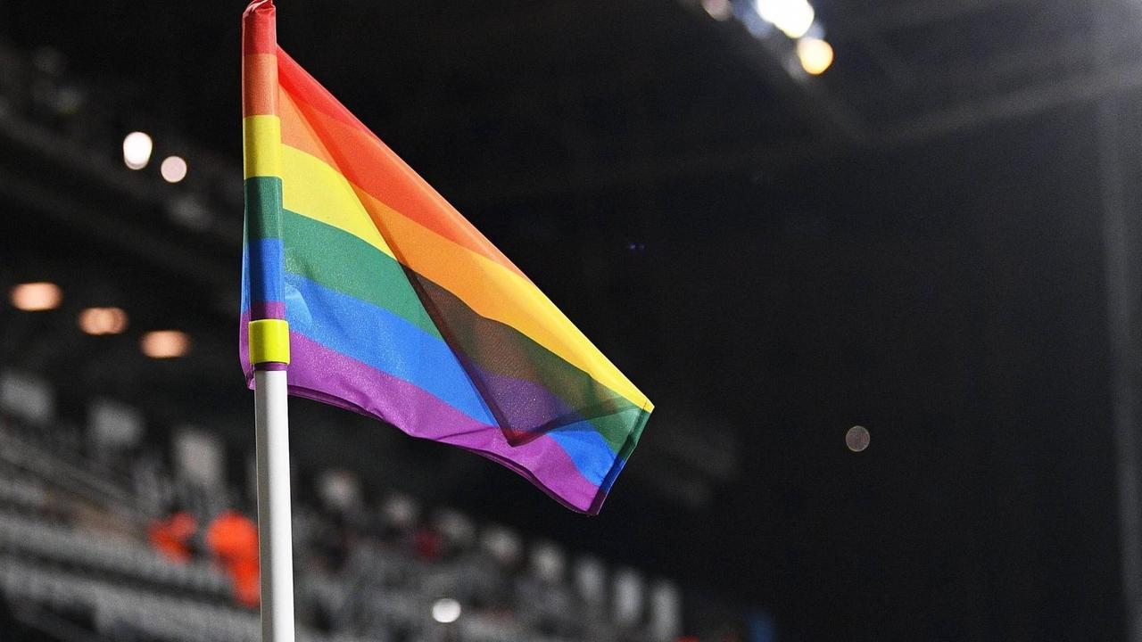 Eine Eckfahne mit den Regenbogenfarben steht in einem Fußballstadion. Eine Eckfahne mit den Regenbogenfarben steht in einem Fußballstadion.