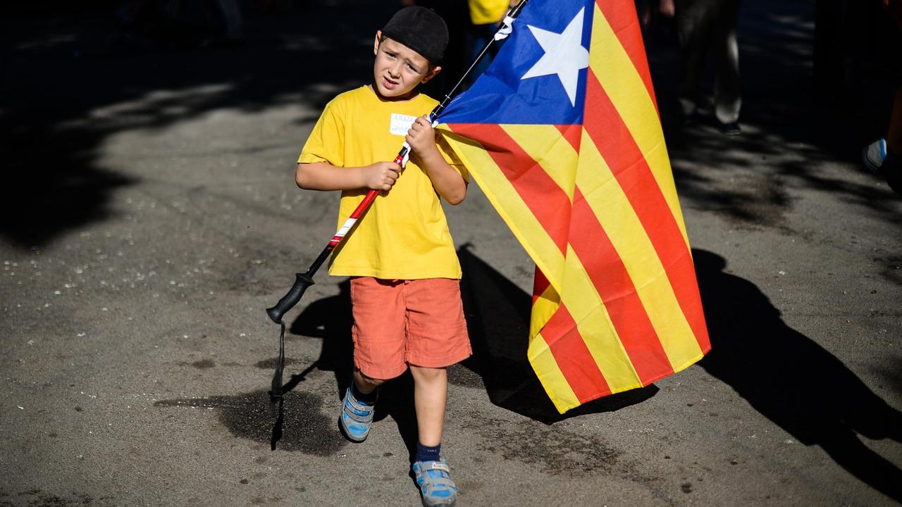 Ein Junge trägt eine katalonische Flagge auf einer Demonstration für das Referendum.