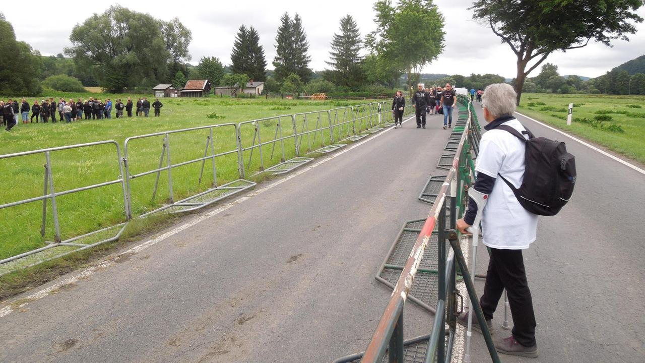 Eine Frau steht vor einer Absperrung. Im Hintergrund nähern sich Besucher des Konzerts "Rock gegen Überfremdung." Eine Frau steht vor einer Absperrung. Im Hintergrund nähern sich Besucher des Konzerts "Rock gegen Überfremdung."