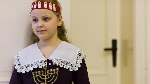 Ein Mädchen wartet mit einem Chanukka-Leuchter in ihren Händen auf den Beginn des jüdischen Lichterfest "Chanukka".