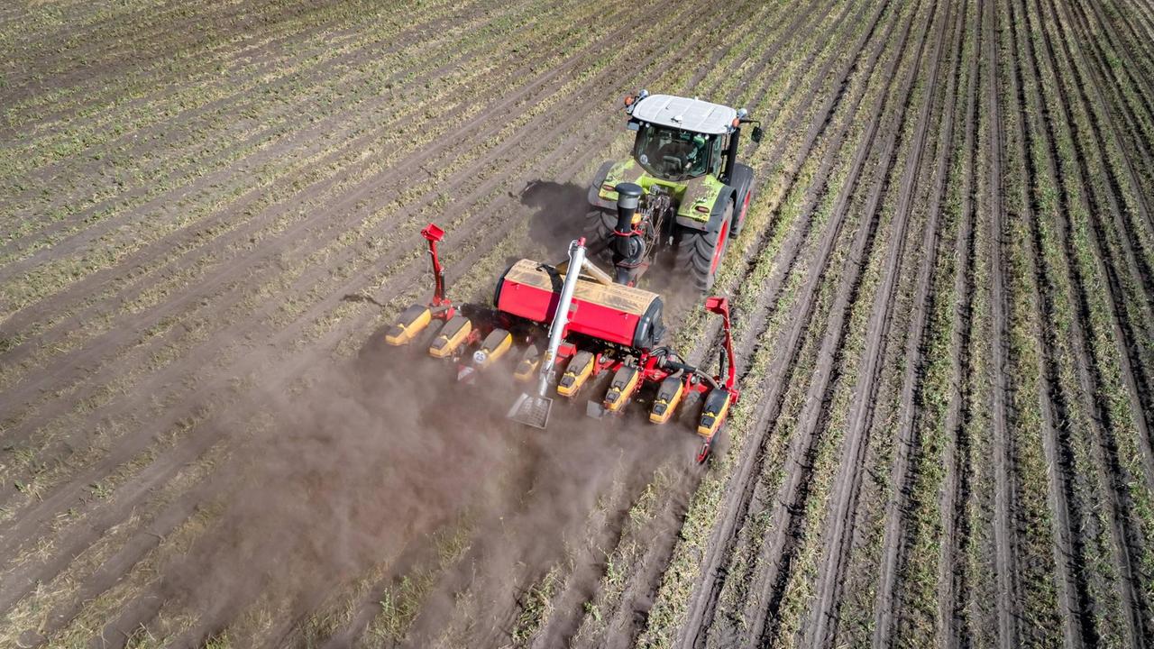 Ein Traktor fährt zur Maisaussaat über ein gefurchtes Feld. Ein Traktor fährt zur Maisaussaat über ein gefurchtes Feld.