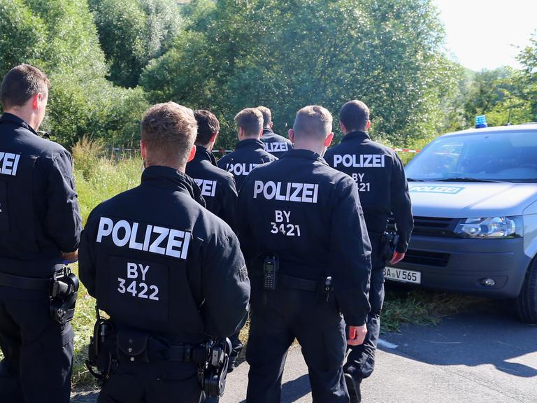 Polizisten durchsuchen am 19.07.2016 neben einem Weg bei Würzburg (Bayern) das Gelände nach Spuren. Am Montagabend war ein 17 Jahre alter Afghane mit einer Axt und einem Messer auf Fahrgäste in einem Regionalzug bei Würzburg-Heidingsfeld losgegangen.