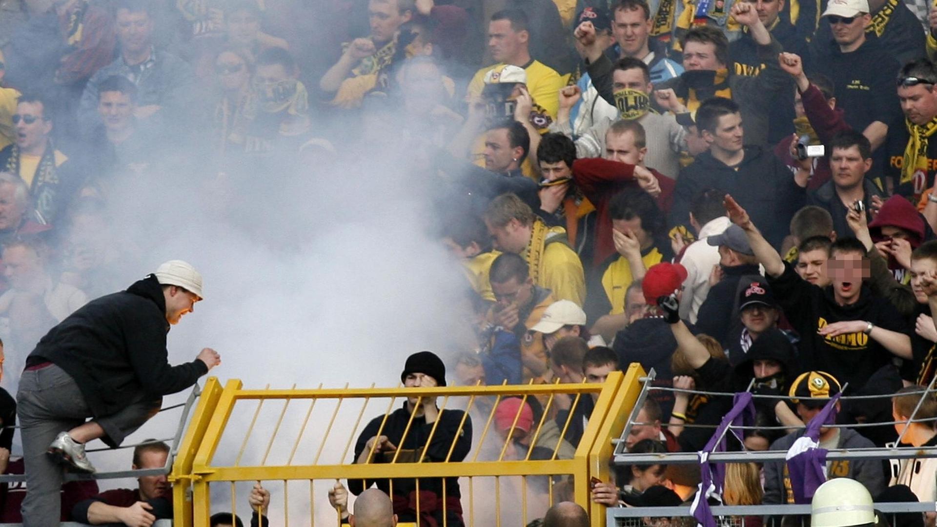 FC Erzgebirge Aue - 1. FC Dynamo Dresden am Sonntag (02.04.2006) im Auer Erzgebirgsstadion. Dresdner Fans zünden während der ersten Halbzeit ein Feuer in ihrem Block, ein Fan mit schwarzem Dynamo-Pullover (r) benutzt den verfassungsfeindlichen "Hitler-Gruß" FC Erzgebirge Aue - 1. FC Dynamo Dresden am Sonntag (02.04.2006) im Auer Erzgebirgsstadion. Dresdner Fans zünden während der ersten Halbzeit ein Feuer in ihrem Block, ein Fan mit schwarzem Dynamo-Pullover (r) benutzt den verfassungsfeindlichen "Hitler-Gruß"