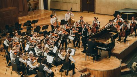 Das Jugendorchester spielt mit einem Pianisten in einem Konzertsaal in Kasan.