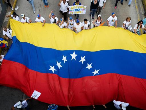 Teilnehmer einer Demonstration gegen Venezuelas Präsident Maduro mit einer venezolanischen Flagge.
