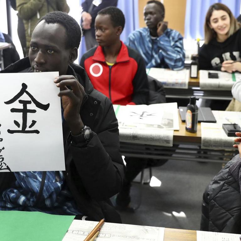 Die südsudanesischen Athleten und Athletinnen üben japanische Schriftzeichen.