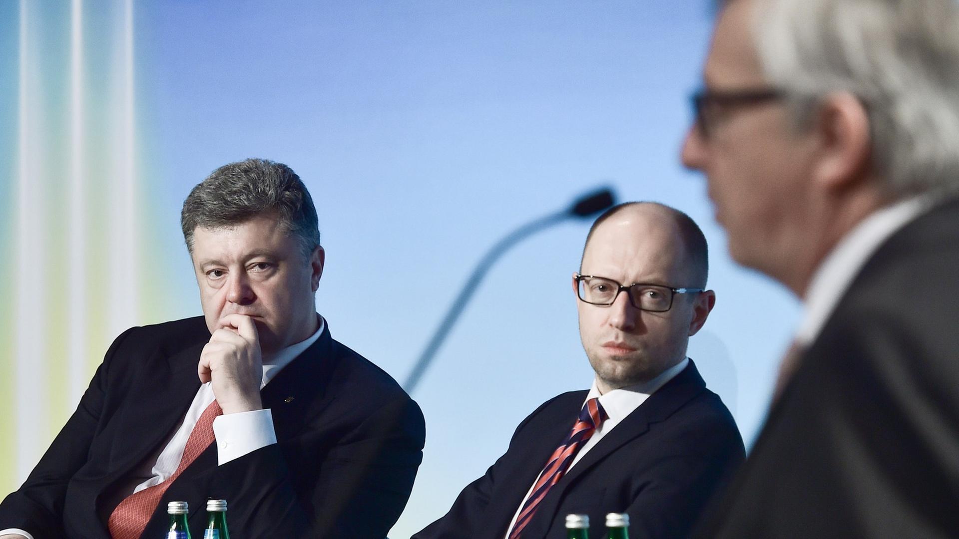Petro Poroschenko und Arseni Jazenjuk hören Jean-Claude Juncker zu. Petro Poroschenko und Arseni Jazenjuk hören Jean-Claude Juncker zu.