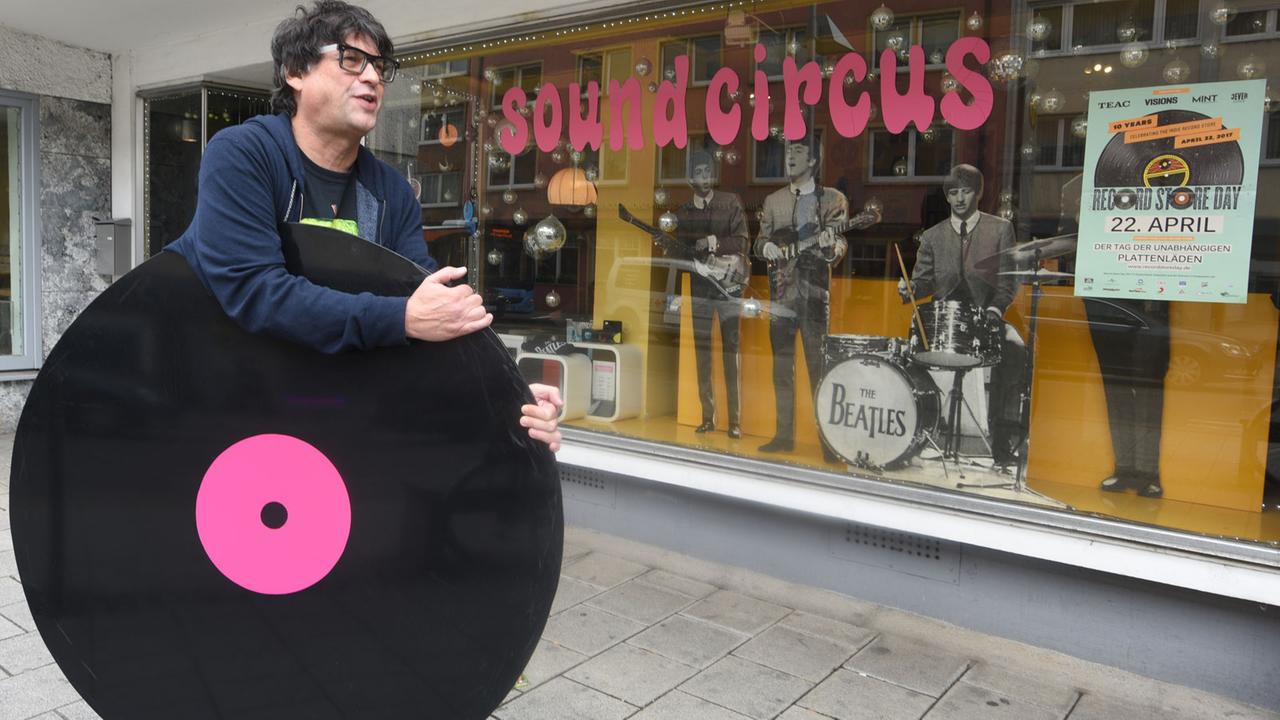 Martin Maag trägt in Ulm vor seinem Laden "Sound Circus" eine überdimensionale Schallplatte. Martin Maag trägt in Ulm vor seinem Laden "Sound Circus" eine überdimensionale Schallplatte.