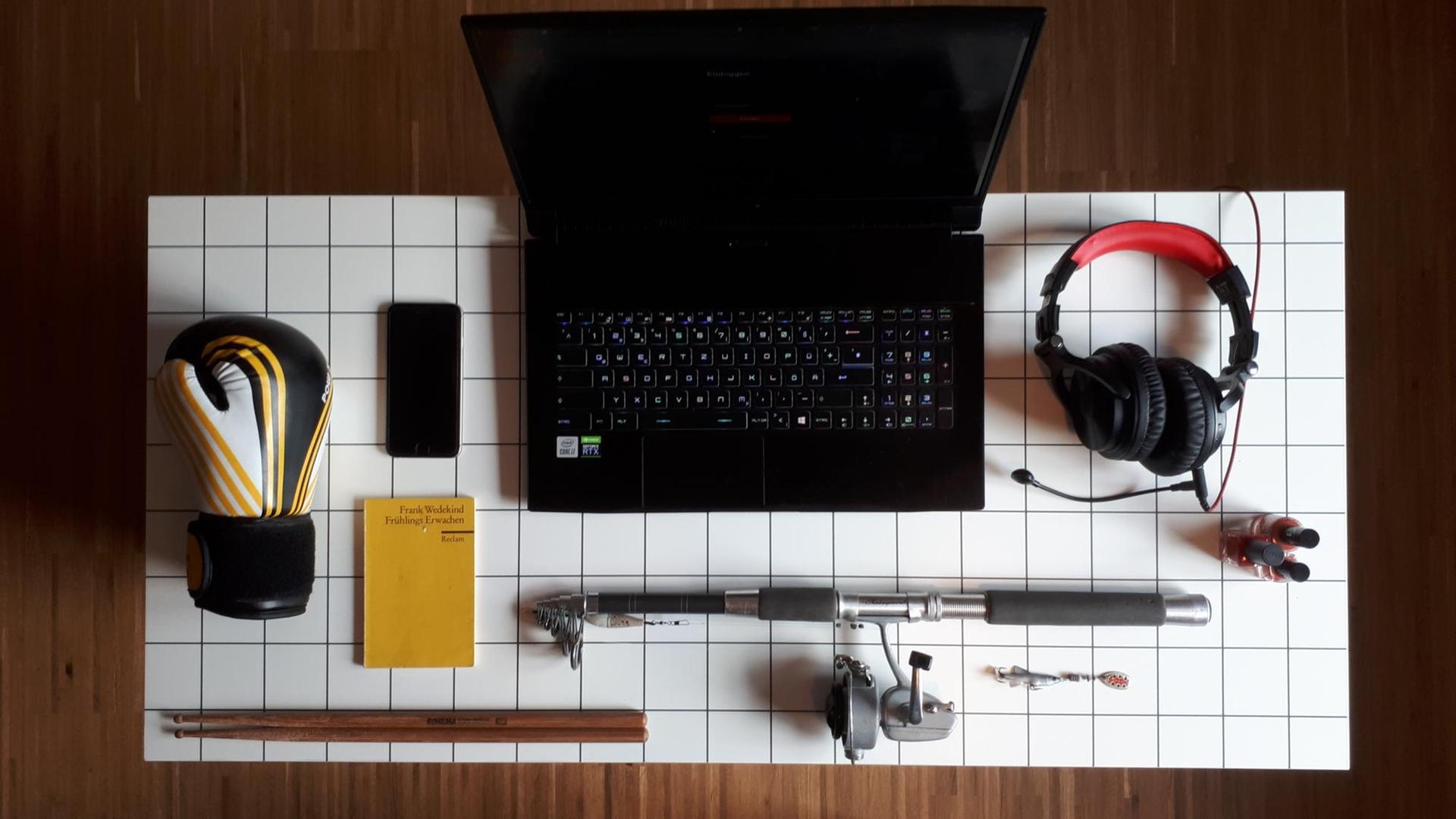 Schreibtisch mit Rechner, Reclamheft, Angel, Headset, Handy, Nagellack, Boxhandschuh, Drumsticks. Schreibtisch mit Rechner, Reclamheft, Angel, Headset, Handy, Nagellack, Boxhandschuh, Drumsticks.