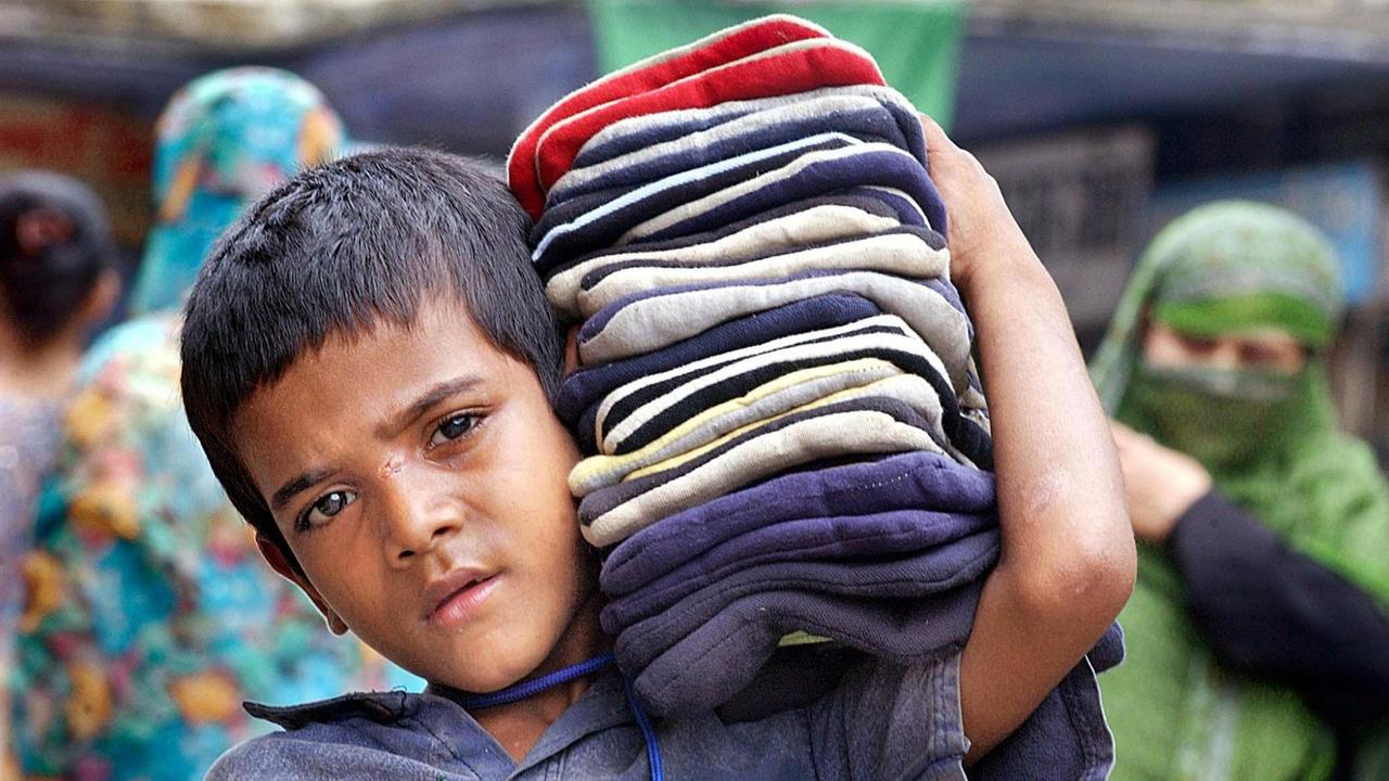 Viele Kinder in Indien müssen arbeiten, meist in Textilfabriken. Man sieht einen Jungen, der Stoffe auf der Schulter trägt. Viele Kinder in Indien müssen arbeiten, meist in Textilfabriken. Man sieht einen Jungen, der Stoffe auf der Schulter trägt.