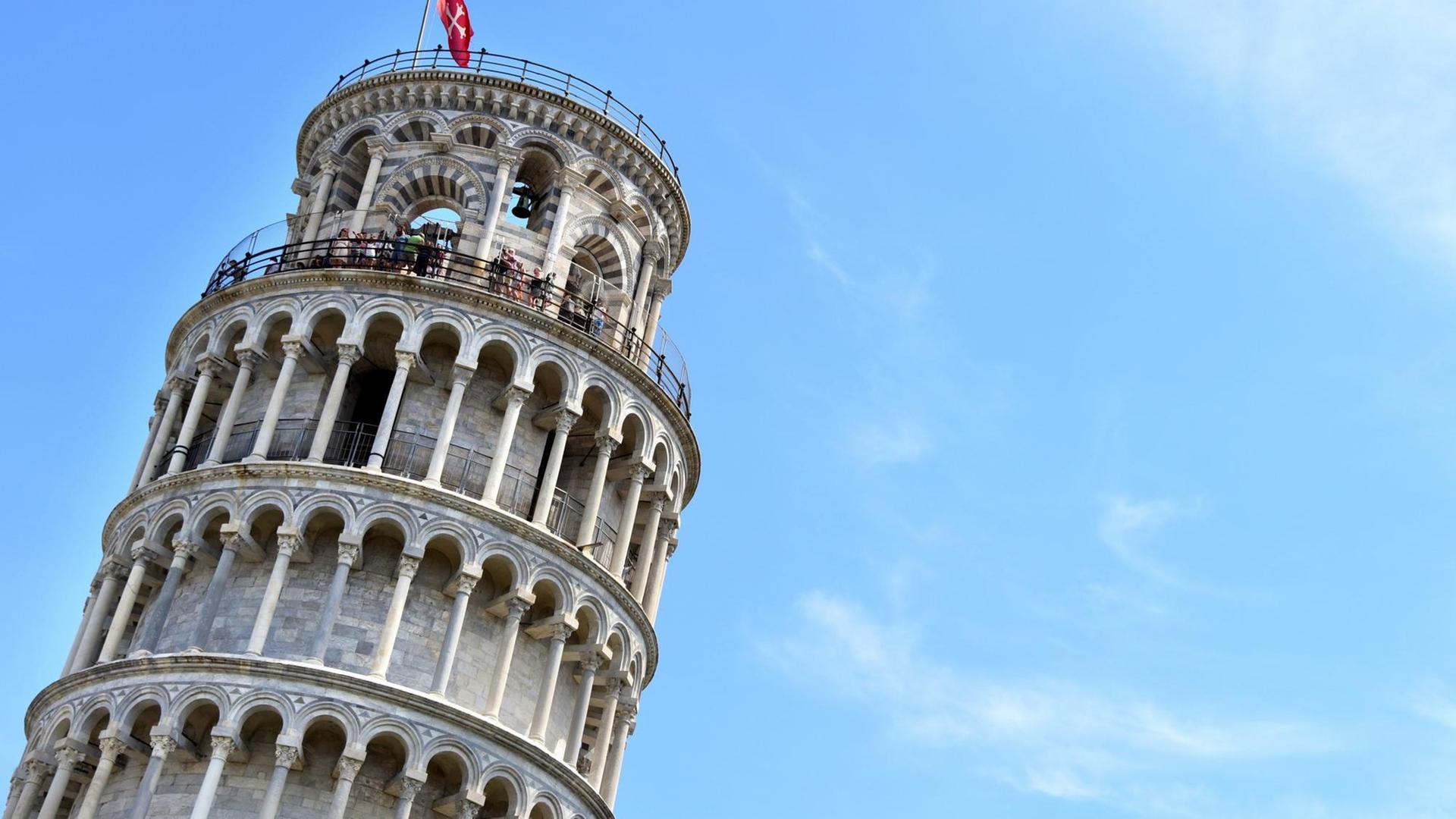 Der Turm ragt schief in den blauen Himmel.