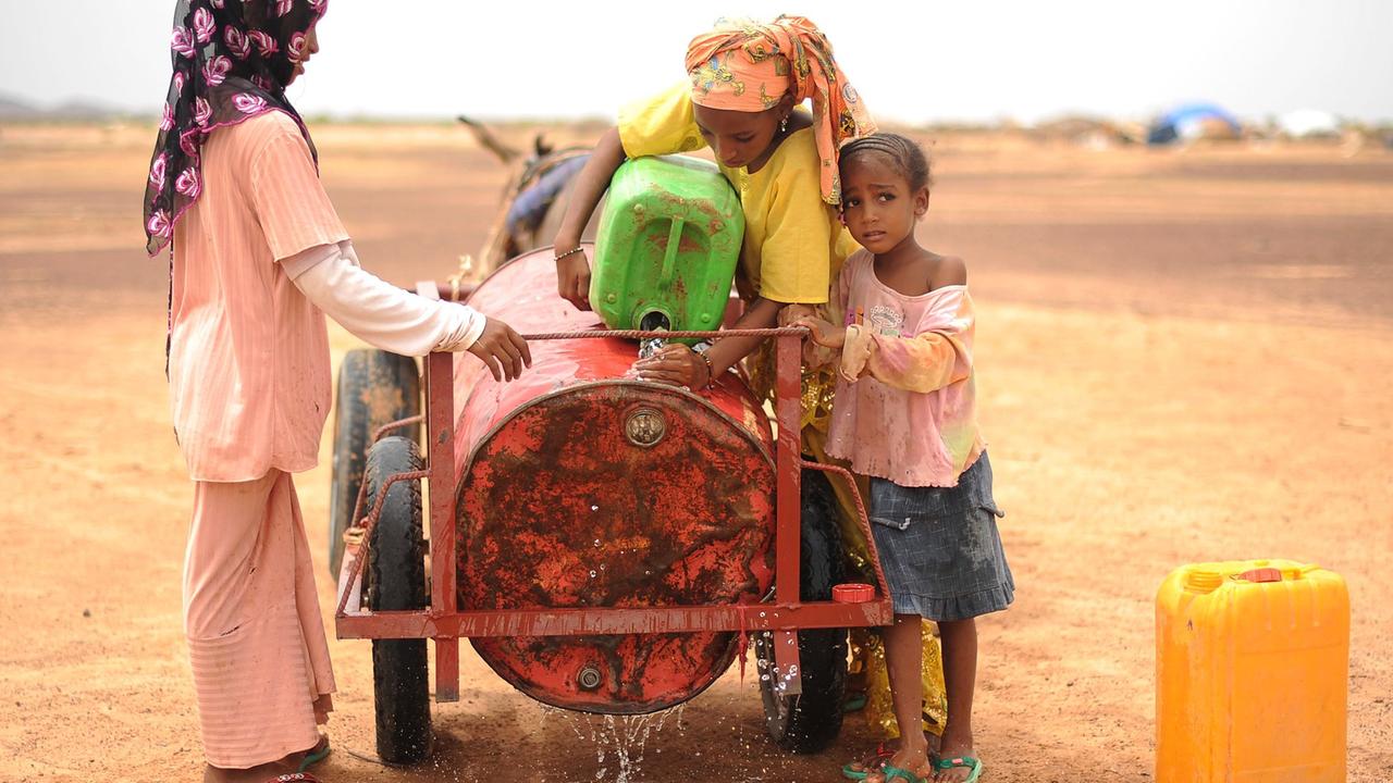 Drei Mädchen aus Mali holen Wasser in einem Flüchtlingscamp in der Nähe von Dori, Burkina Faso. Drei Mädchen aus Mali holen Wasser in einem Flüchtlingscamp in der Nähe von Dori, Burkina Faso.
