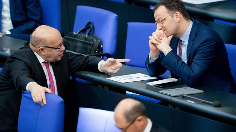 Peter Altmaier (l, CDU), Bundesminister für Wirtschaft und Energie, und Jens Spahn (r, CDU), Bundesminister für Gesundheit, unterhalten sich während der 154. Sitzung des Bundestages hinter Olaf Scholz (SPD), Bundesminister der Finanzen. 