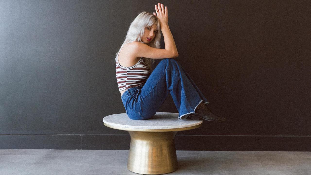 US-Musikerin Mikaela Davis hockt auf einem Couchtisch