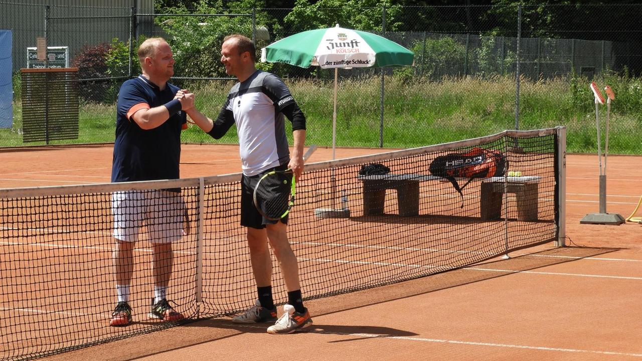 Zwei Tennisspieler geben sich am Netz auf dem Tennisplatz die Hand Zwei Tennisspieler geben sich am Netz auf dem Tennisplatz die Hand