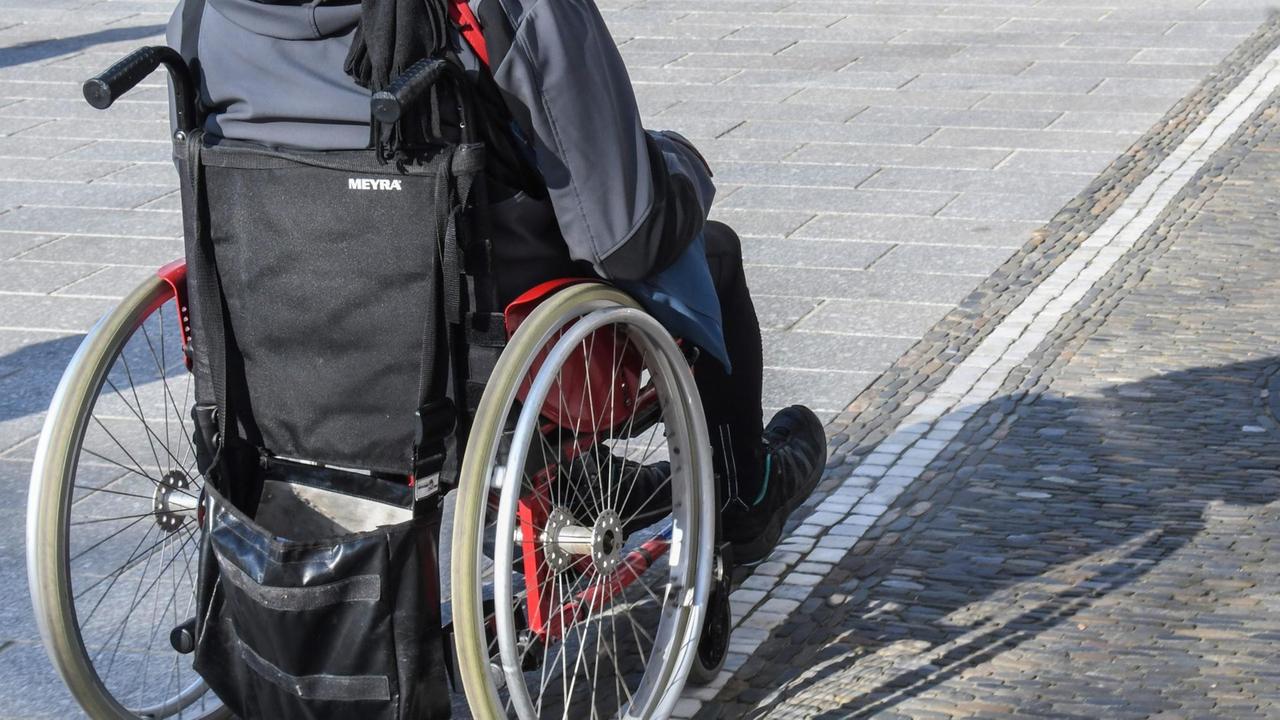 Ein Rollstuhlfahrer über Kopfsteinpflaster unterwegs